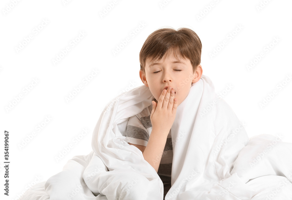 Yawning little boy wrapped in blanket on white background