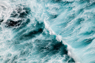 Blue and white wave creating ocean pattern, aerial perspective.