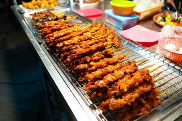 Wall Mural - Asian food. A counter with mini kebabs of chicken skin and meat at a nightly street food market.