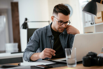 Young businessman using laptop in his office.  Handsome man working in office.	