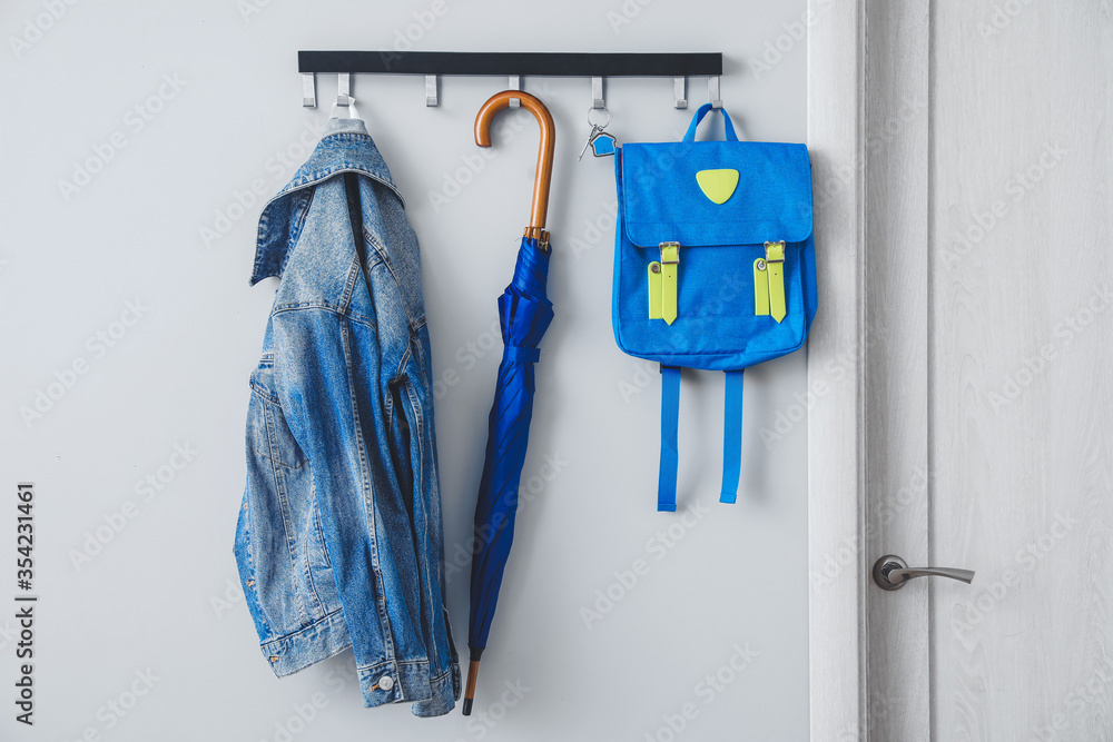 Umbrella with clothes and school backpack hanging on wall in hall