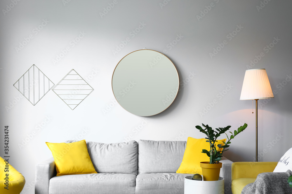 Stylish interior of living room with mirror and sofa