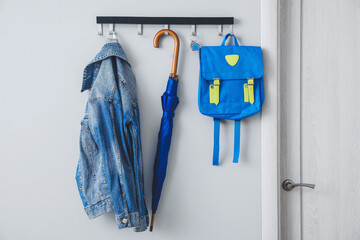 Umbrella with clothes and school backpack hanging on wall in hall