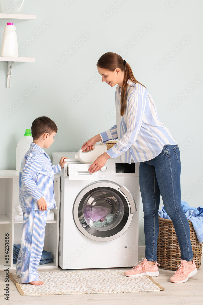 Young woman with her little son doing laundry at home