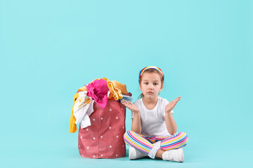 Wall Mural - Little girl with dirty laundry on color background