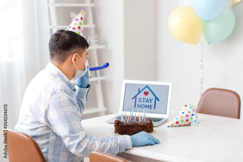 Asian man with laptop on his Birthday at home. Concept of epidemic