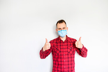 Wall Mural - Protect yourself during pandemic. A young man showing thumbs up on medical mask on his face. Saving from allergic, smog, virus