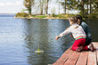 © Ludmila - Two little sisters are sitting on wooden walkways and letting a paper boat into the lake.