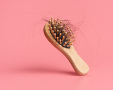 Black Hair Loss Problem With Hairbrush On Pink Background