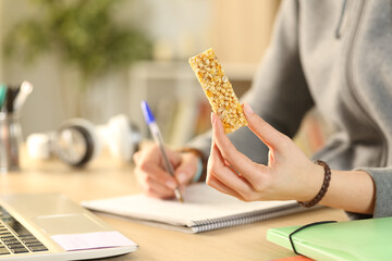 Wall Mural - Student hands holding cereal snack bar studying