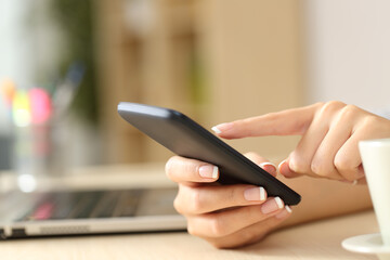 Woman hands using cell phone on a desk at home