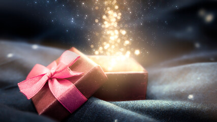 Gift box on a dark magic background with light bokeh. Festive background, magic box with a gift. Dark abstract background with gold bokeh.