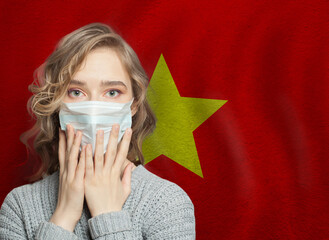 Wall Mural - Scared woman in medical mask on Vietnamese flag background. Flu epidemic and domestic violence in Vietnam concept