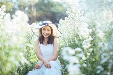 Young beautiful woman in a white dress posing in white flower garden