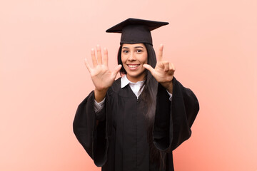 young latin woman student smiling and looking friendly, showing number seven or seventh with hand forward, counting down