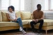 African ethnicity family break up and separation concept. American wife and husband couple after quarrel seated on couch apart in silence thinking having relations problems and lack of understanding