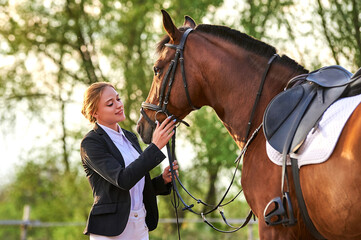 Beautiful horse rider girl stands near a horse on a farm 