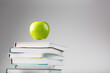 © Alexander - Apple green hanging over books isolate on a white background.