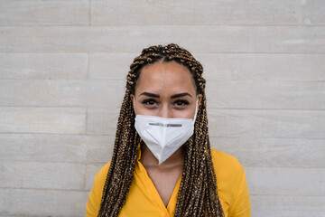 Wall Mural - Young mixed race woman with protective face mask - African woman belongs to the risk group and protects herself - Focus on her face