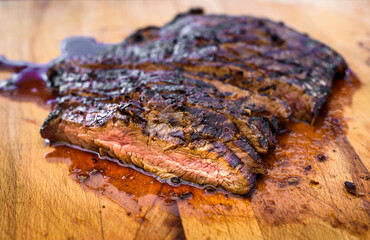 Wall Mural - Sliced grilled juicy marinated angus beef flank steak on wooden board.