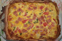 Close Up Of Quiche Fresh From Hot Oven, Homebaked With Organic Vegetables And Ham With Rich Crust Pastry Baked With Eggs Tomato And Cheese In Pie Dish