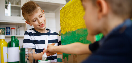 Wall Mural - Brothers painting a cardboard dinosaur costume	
