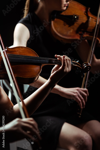 Plakaty filharmonia  czesciowy-widok-dwoch-profesjonalnych-muzykow-grajacych-na-skrzypcach-na-ciemnej-scenie