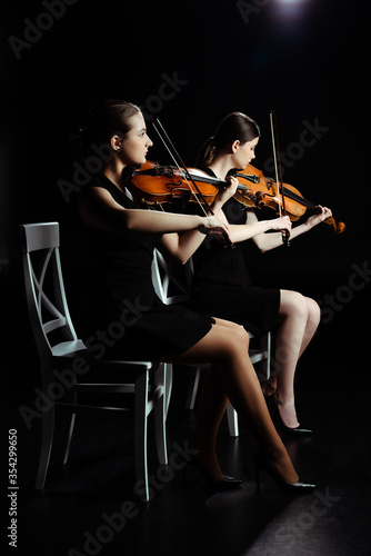 Dekoracja na wymiar  profesjonalni-mlodzi-muzycy-grajacy-muzyke-klasyczna-na-skrzypcach-na-ciemnej-scenie