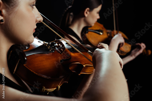 Dekoracja na wymiar  mlodzi-profesjonalni-muzycy-grajacy-muzyke-klasyczna-na-skrzypcach-na-ciemnej-scenie