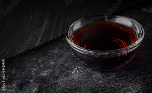 Soy sauce in small glass dish black background