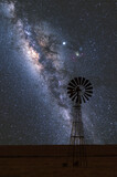 Fototapeta  - Wiatrak na farmie i nocne niebo gwiezdziste z centrum Drogi Mlecznej w bezksiężycową noc