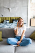 © F8  \ Suport Ukraine - Casual young woman using mobile phone while sitting on couch at home