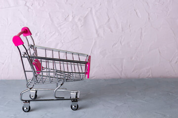 Baskets shopping cart or shopping trolley on concrete surface background. Selective focus.