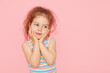 © oes - Portrait of surprised cute little toddler girl child over pink background. Looking at camera. Points hands to the left side. Advertising childrens products