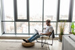 © F8  \ Suport Ukraine - Portrait of a smiling man relaxing on chair near window ise laptop