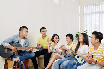 Poster - Cheerful young Vietnamese people paying guitars and singing at home