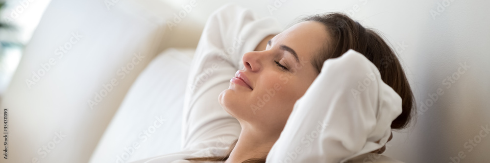 Serene woman leaned on comfy sofa put hands behind head resting in living room close up, enjoy carefree free day, breathing fresh air feels peaceful. Horizontal photo banner for website header design - obrazy, fototapety, plakaty 