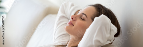 Fotomural Serene woman leaned on comfy sofa put hands behind head resting in living room close up, enjoy carefree free day, breathing fresh air feels peaceful
