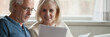 © fizkes - Elderly spouses read paper from bank, analyzing financial statement manage together family budget feels satisfied, enough money, taxes refund concept. Horizontal photo banner for website header design