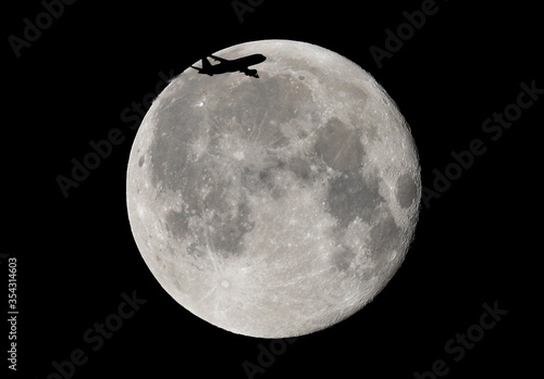 Księżyc dzień po pełni i przelatujący samolot na tle tarczy.