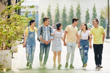 Canvas Print - Happy positive friends laughing and joking around when walking in the street