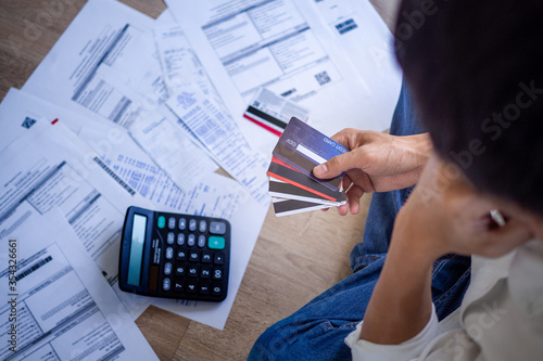 Business people are stressed about credit card debt and many bills on the floor. Men get trouble by calculating monthly expenses and then budgeting not enough money for paying debts.