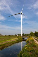 Sticker - White wind turbine next to the water surrounded by trees and grass