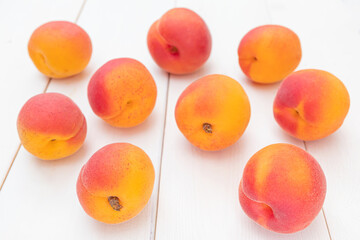 Wall Mural - Ripe bright apricots lie on a white wooden surface. Summer fruit harvest.