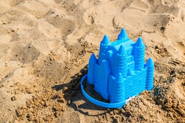 Closeup shot of a blue mini castle-shaped sandbox toy at the beach under the sunlight