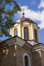 Orthodox Church With A Bell Tower. Two Crosses On The Roof. In The Foreground Yellow And Green Bushes And Trees
