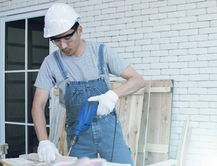 A carpenter is making a hold on wood by using a drill