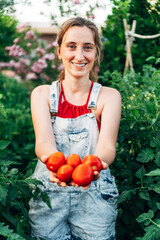 woman with vegetables in her hand looks at the camera with a smile. the farmer gathers the harvest i