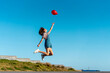 © VISTA by Westend61 - Jumping young woman, letting go of a red ballon