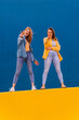 © VISTA by Westend61 - Young women standing on an orange wall and showing peace sign